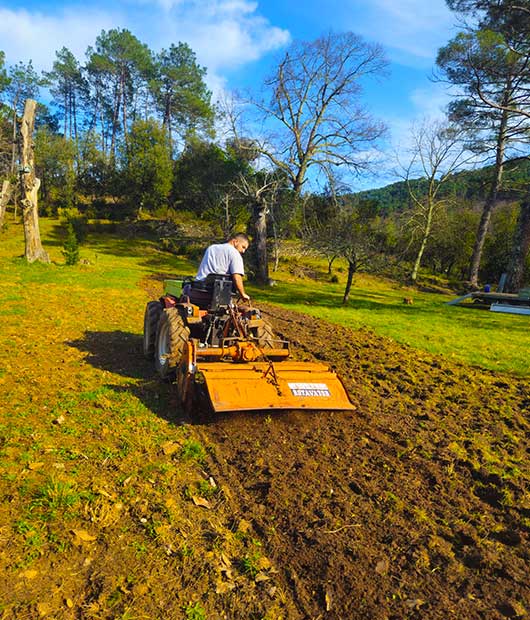 Un homme labourant la terre avec un tracteur.